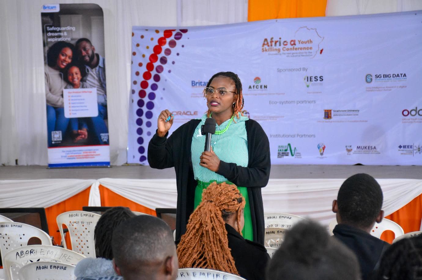 A speaker at the microphone, sponsors’ banner behind.
